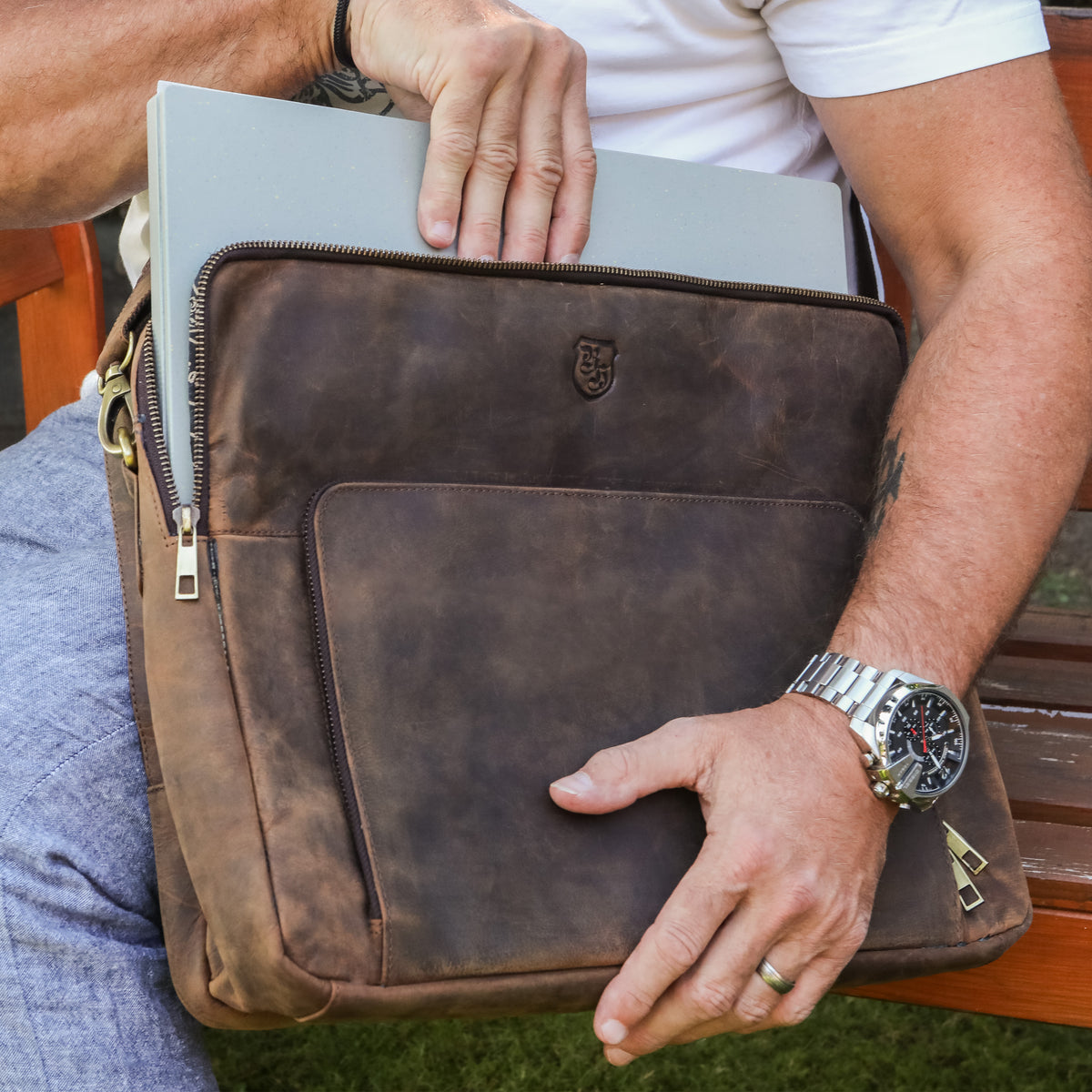 Mann steckt Laptop in braune Hodalump Laptoptasche aus Leder im Vintage Stil.