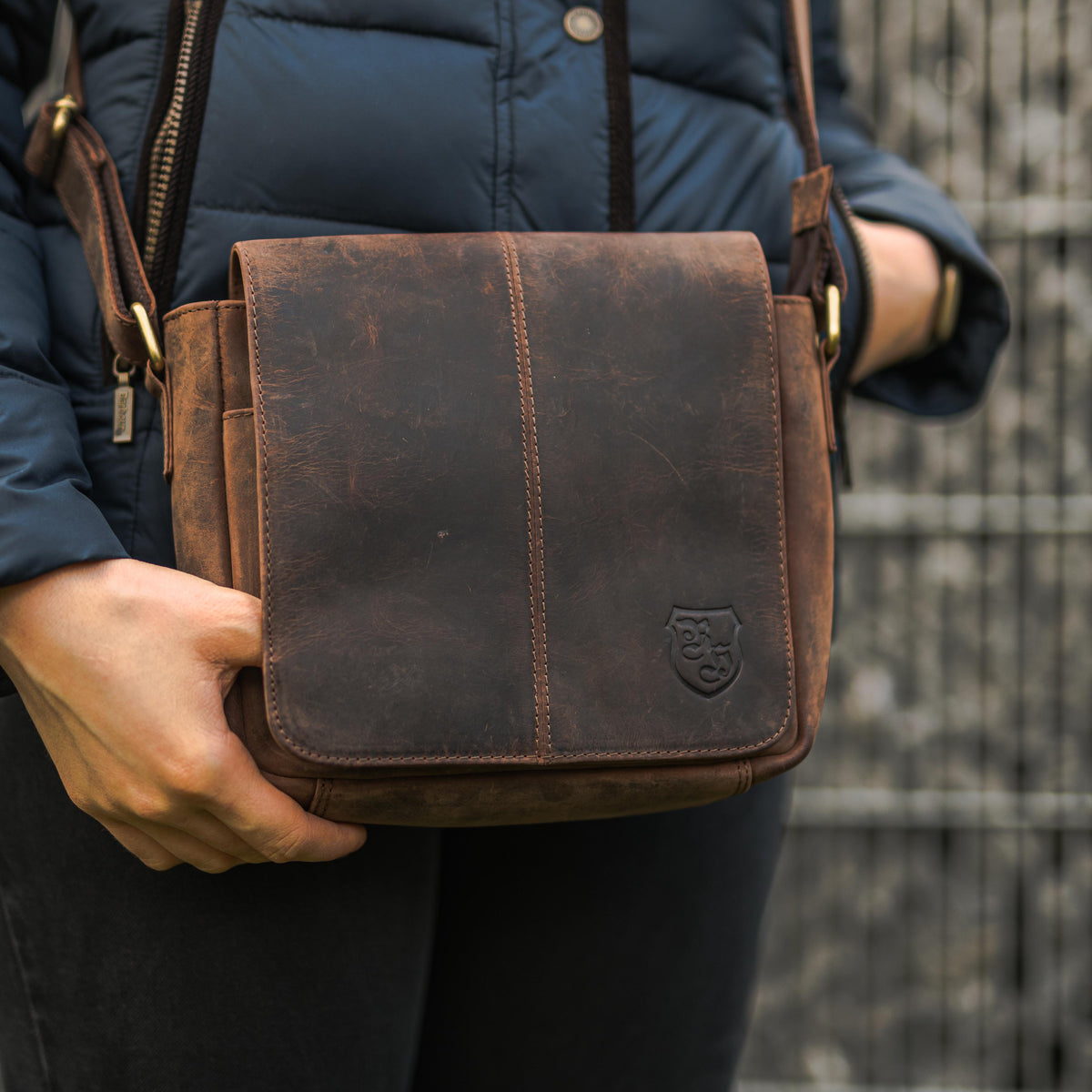 Person trägt braune Hodalump Umhängetasche aus Leder mit Klappe im Vintage Stil.